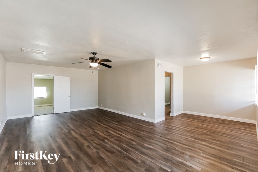 an empty living room with wood flooring and a ceiling fan