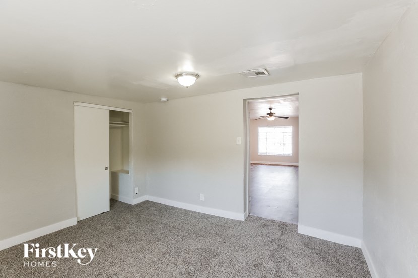 the living room of an empty house with a hallway and a door to the kitchen