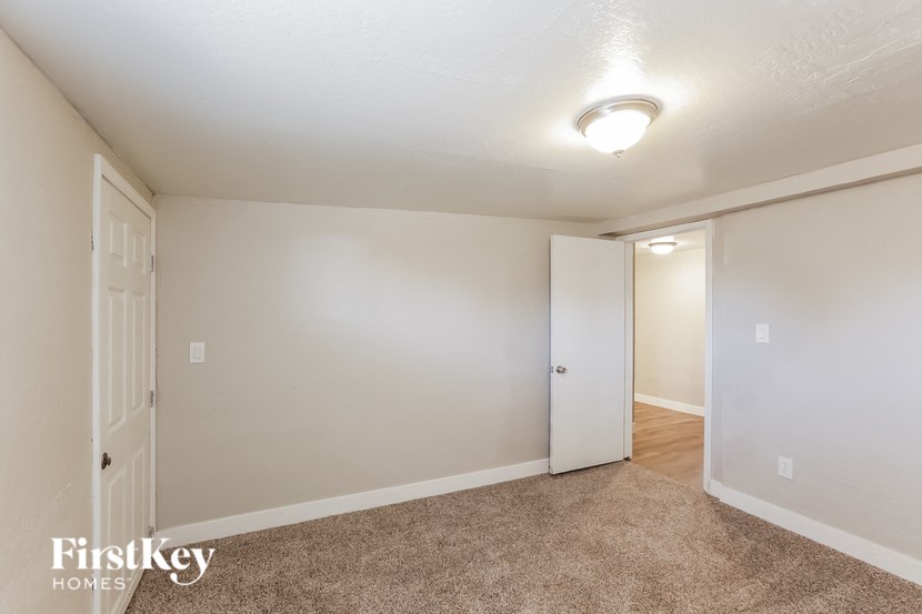 the living room of an apartment with carpet and a door to the hallway