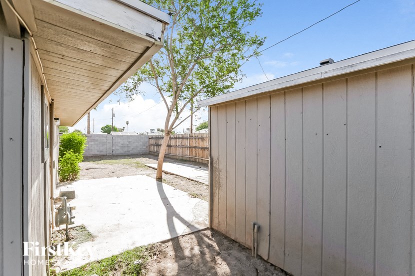 a backyard with a white fence and a white shed and a tree
