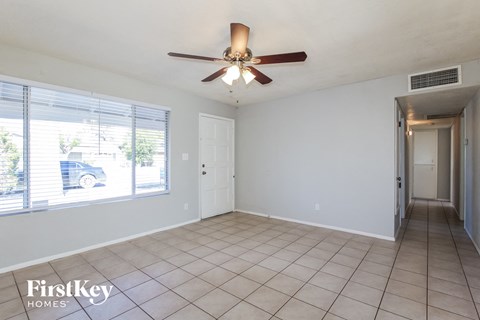 an empty living room with a ceiling fan and a large window