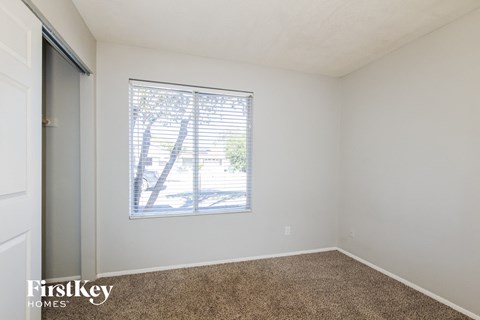 a bedroom with a window and a carpeted floor