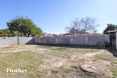 the backyard of a house with a concrete fence and a yard with grass