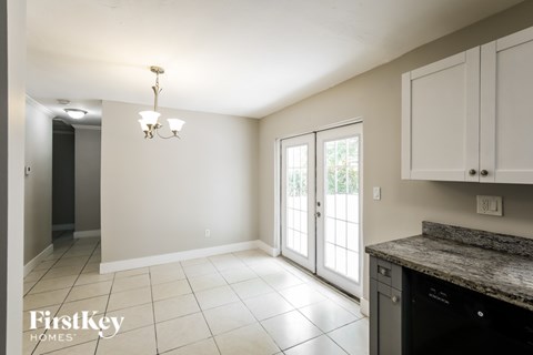 A kitchen area with a granite countertop and white cabinets.