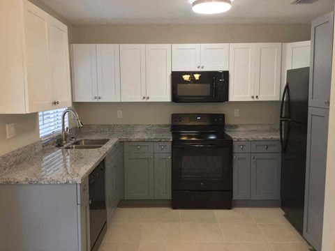 A kitchen with black appliances and white cabinets.