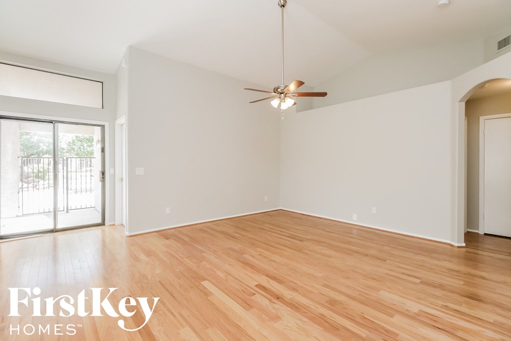 an empty living room with wood flooring and a ceiling fan