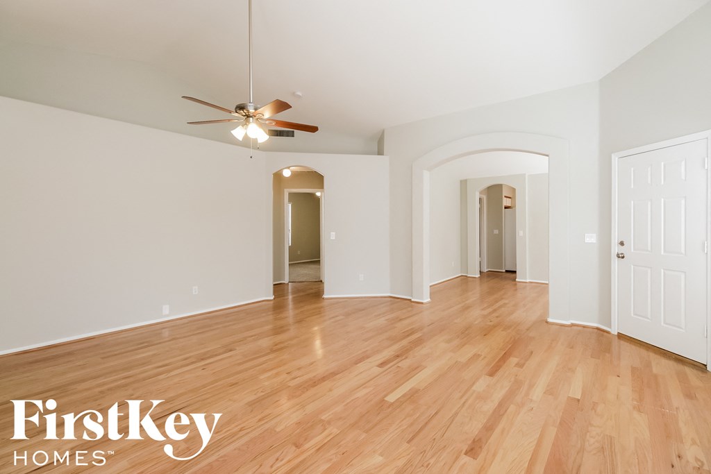 a spacious living room with hardwood floors and a ceiling fan
