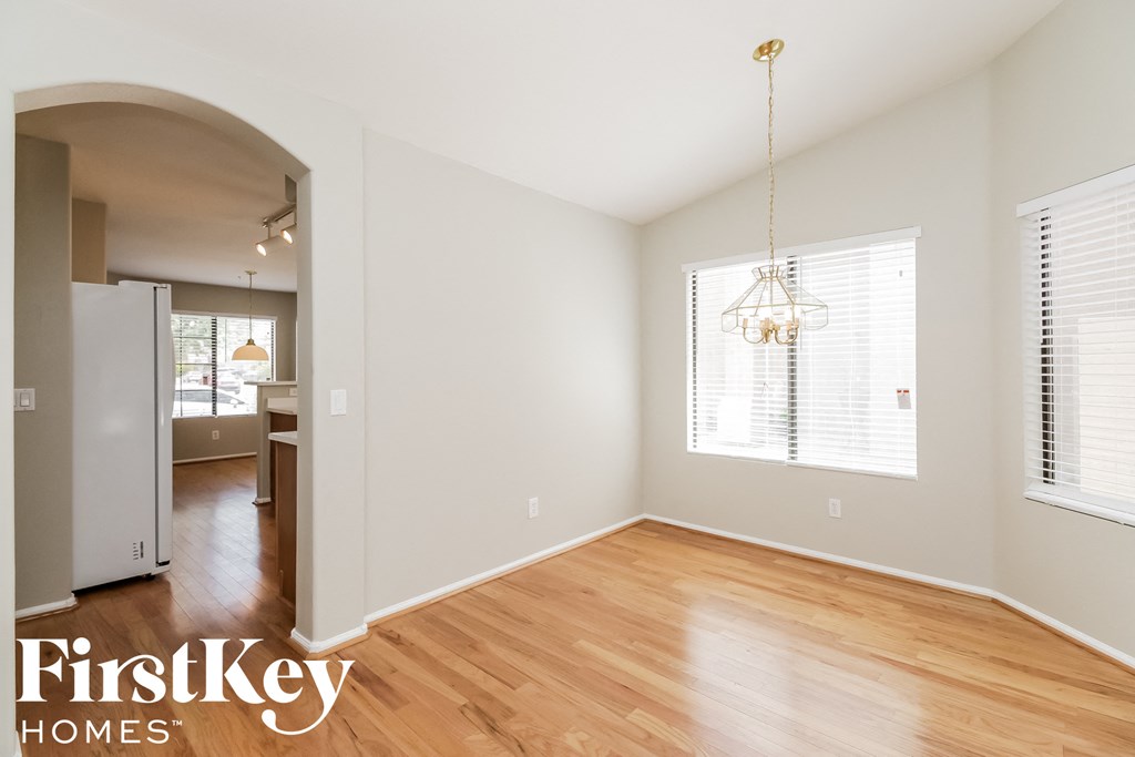 an empty living room with wood flooring and a kitchen