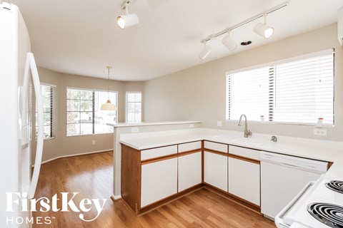 a kitchen with white cabinets and white appliances and a wood floor