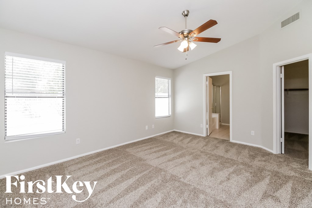 a spacious living room with carpet and a ceiling fan