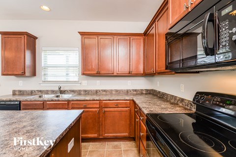 a kitchen with wood cabinets and black appliances and granite counter tops