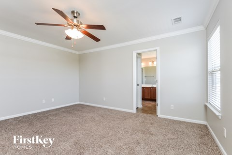 a living room with a ceiling fan and a carpet