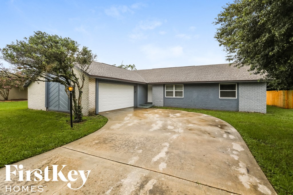 a blue and white house with a driveway and grass