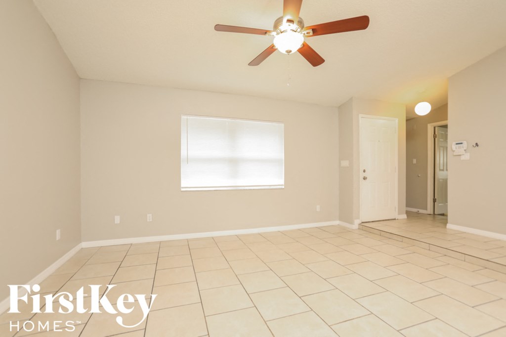 a clean and empty living room with a ceiling fan