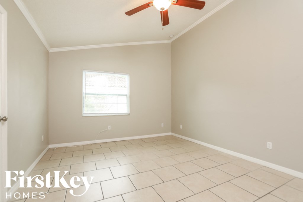 a empty living room with a ceiling fan and tiled floors