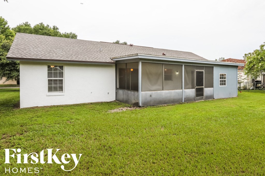 the backyard of a white house with a grassy yard and