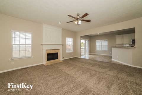 an empty living room with a ceiling fan and a fireplace
