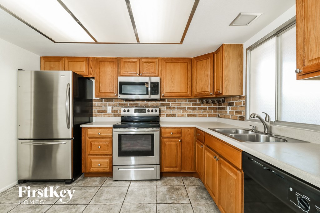 A kitchen with wooden cabinets and a stainless steel refrigerator.