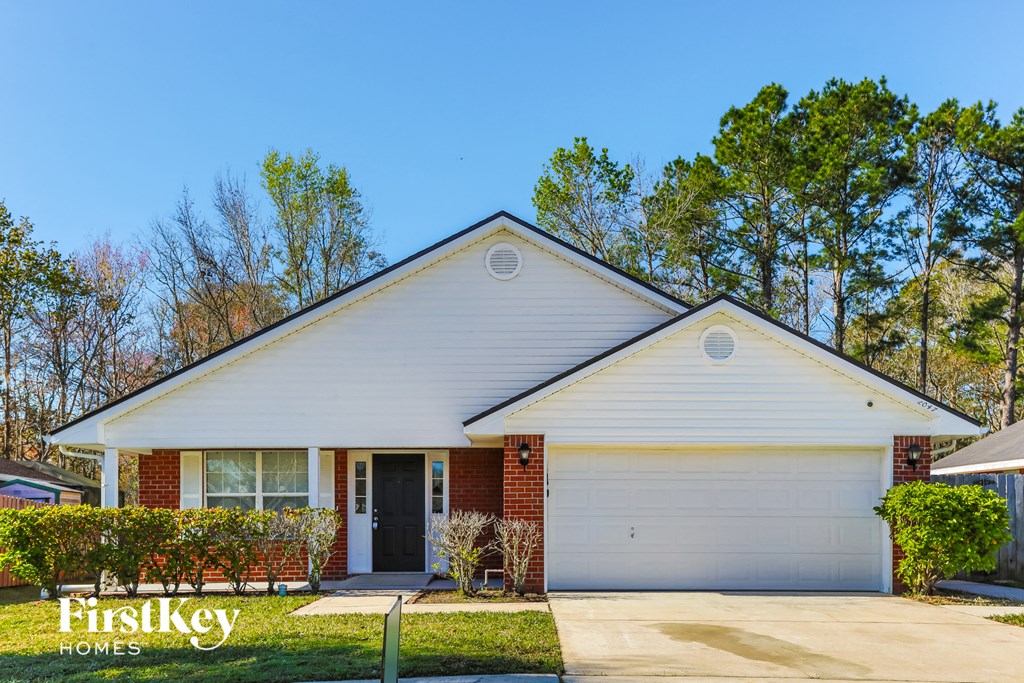A white house with a garage door and a sign that says "FirstKey Homes".