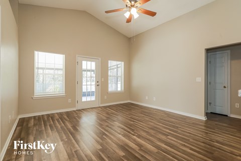 A spacious room with wooden floors and a ceiling fan.