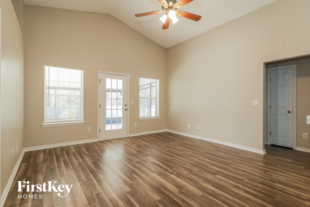 A spacious room with wooden floors and a ceiling fan.