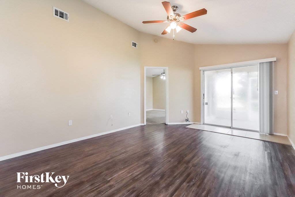 an empty living room with hardwood flooring and a ceiling fan