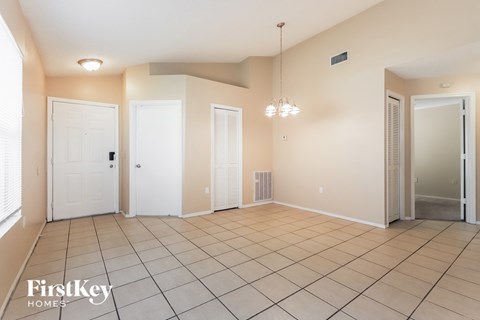 a spacious living room with a tiled floor and two closets