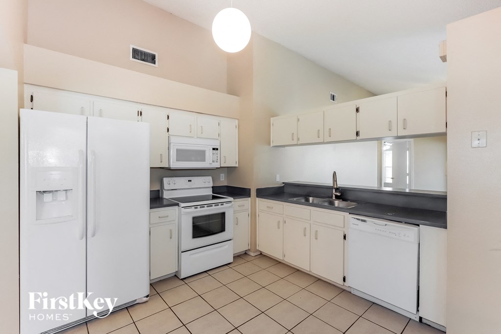 a kitchen with white appliances and white cabinets and tiled floors