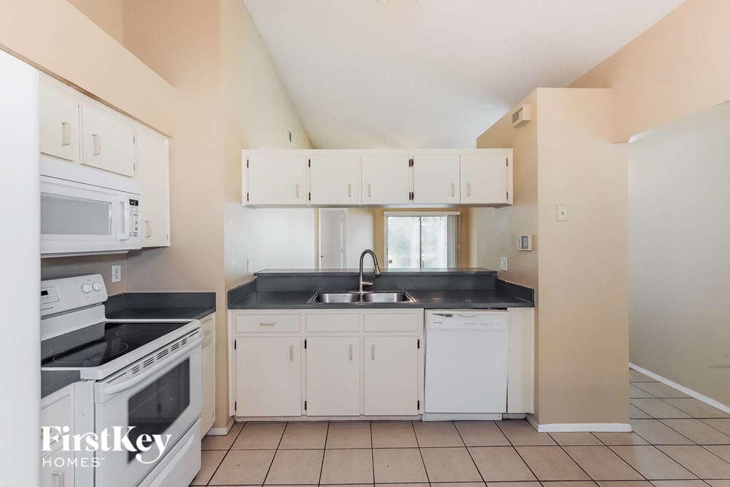 a kitchen with white cabinets and a sink and stove and a microwave