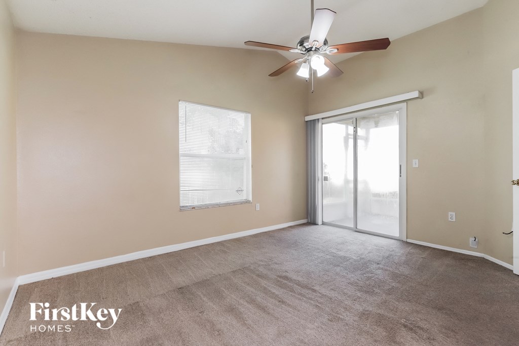 an empty living room with a ceiling fan and a sliding glass door