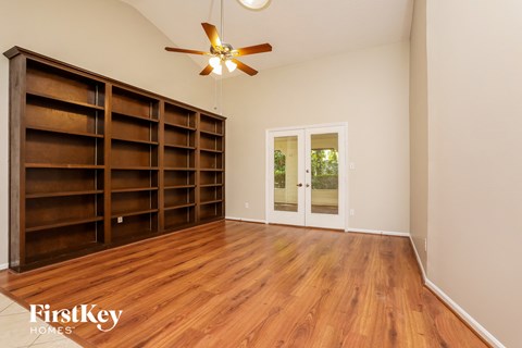 a living room with a bookshelf and a ceiling fan