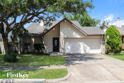 a white house with a garage door and a tree