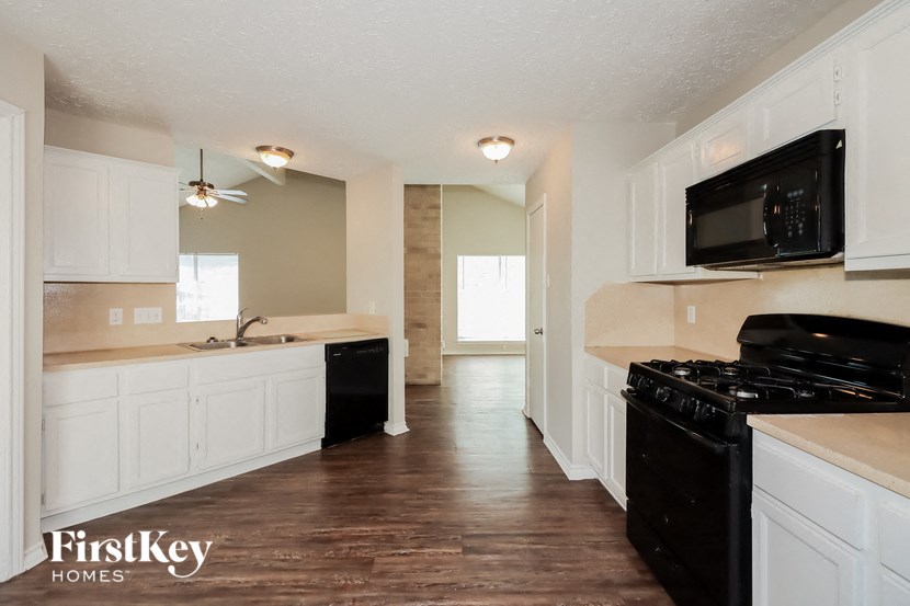 an empty kitchen with white cabinets and a black stove