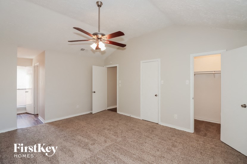 an empty living room with a ceiling fan and white walls