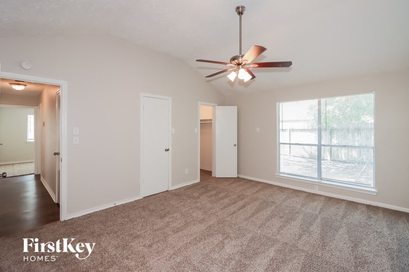 an empty living room with a ceiling fan and a large window