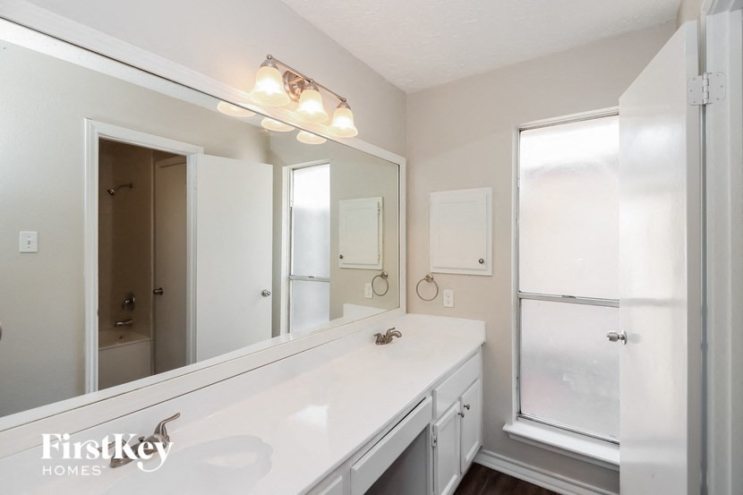 a white bathroom with a large mirror and a white sink