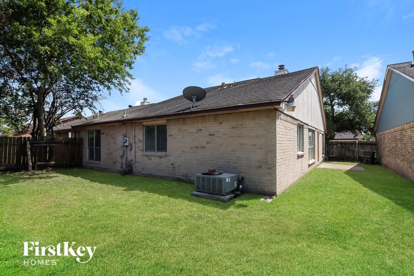 a small brick house with a backyard and a satellite dish on the roof