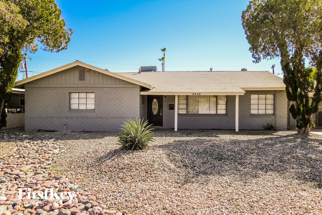 a white house with a gravel driveway and trees