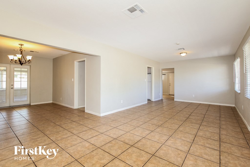 an empty living room with tile flooring and white walls