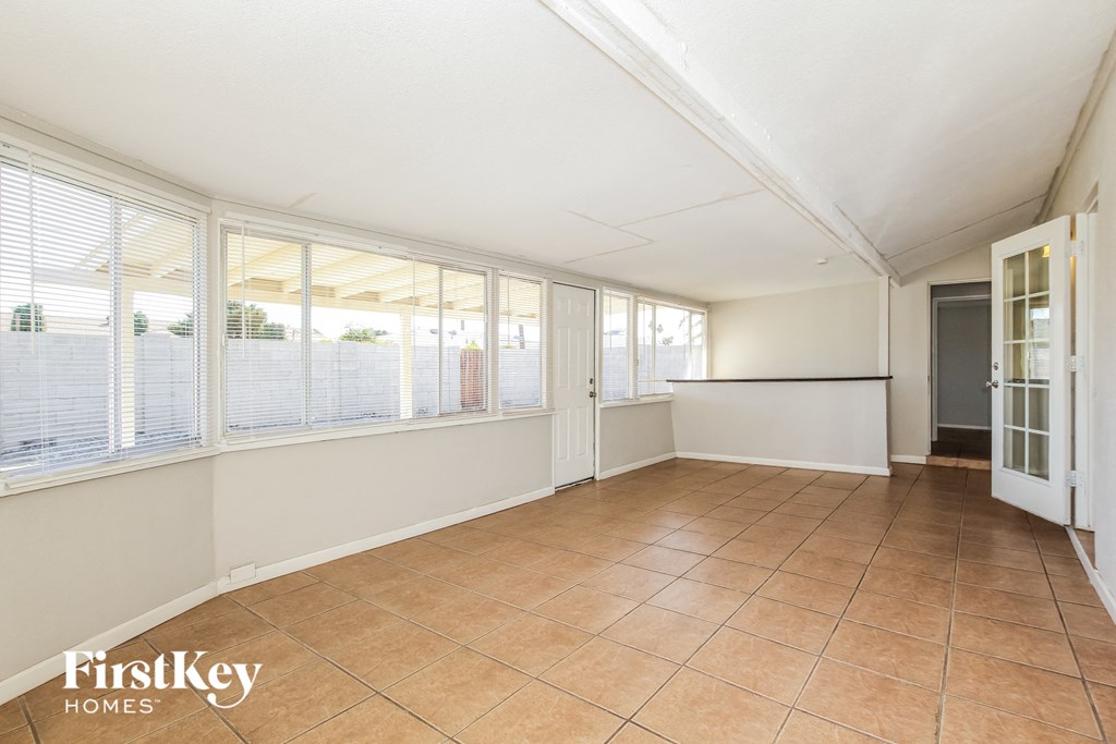 an empty living room with large windows and a tiled floor