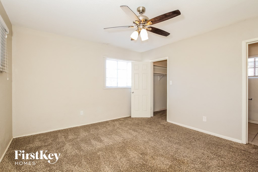 the spacious living room with ceiling fan and carpeting