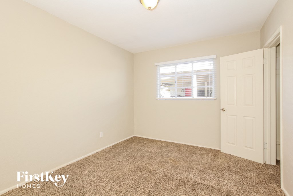 a bedroom with carpet and a white door and window