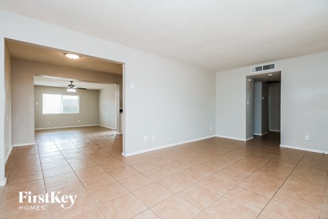 A spacious room with a tiled floor and a ceiling fan.