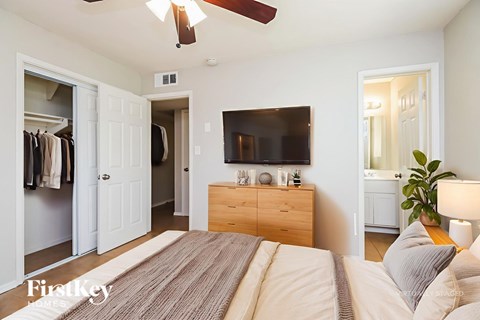 A bedroom with a bed, a dresser, a mirror, and a television.