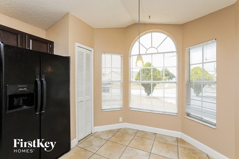 a kitchen with a large window and a black refrigerator