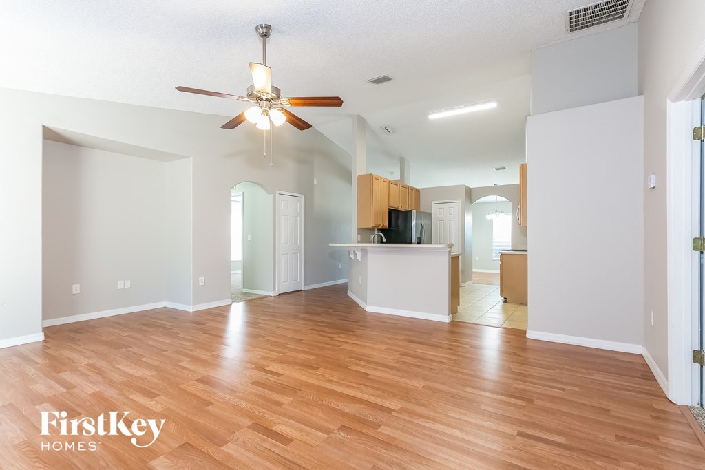 an empty living room with wood flooring and a ceiling fan