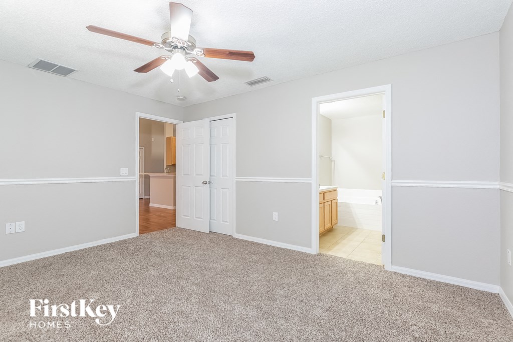 an empty living room with a ceiling fan and a carpet