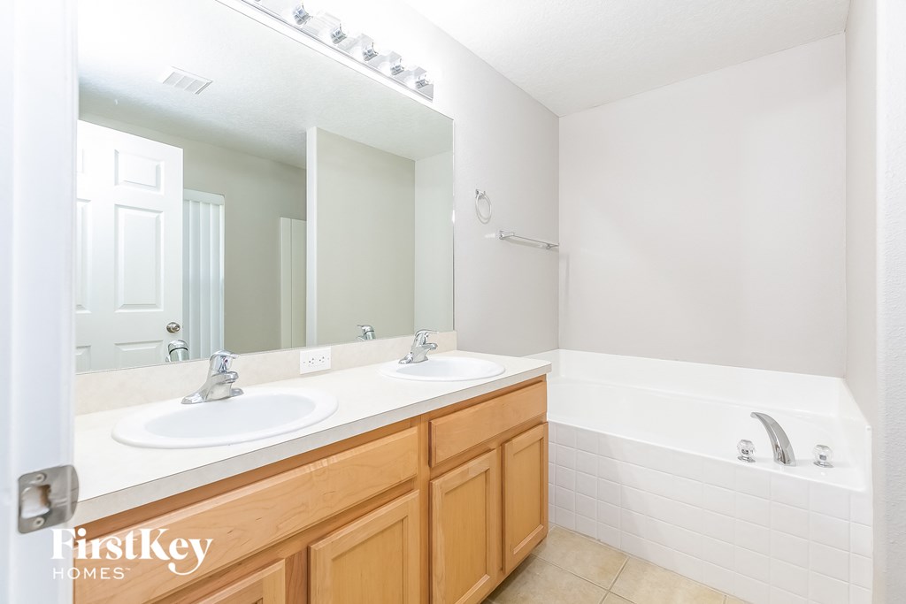 a bathroom with two sinks and a tub and a large mirror