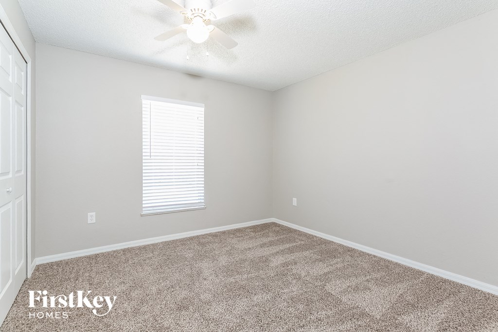 a bedroom with a carpeted floor and a ceiling fan