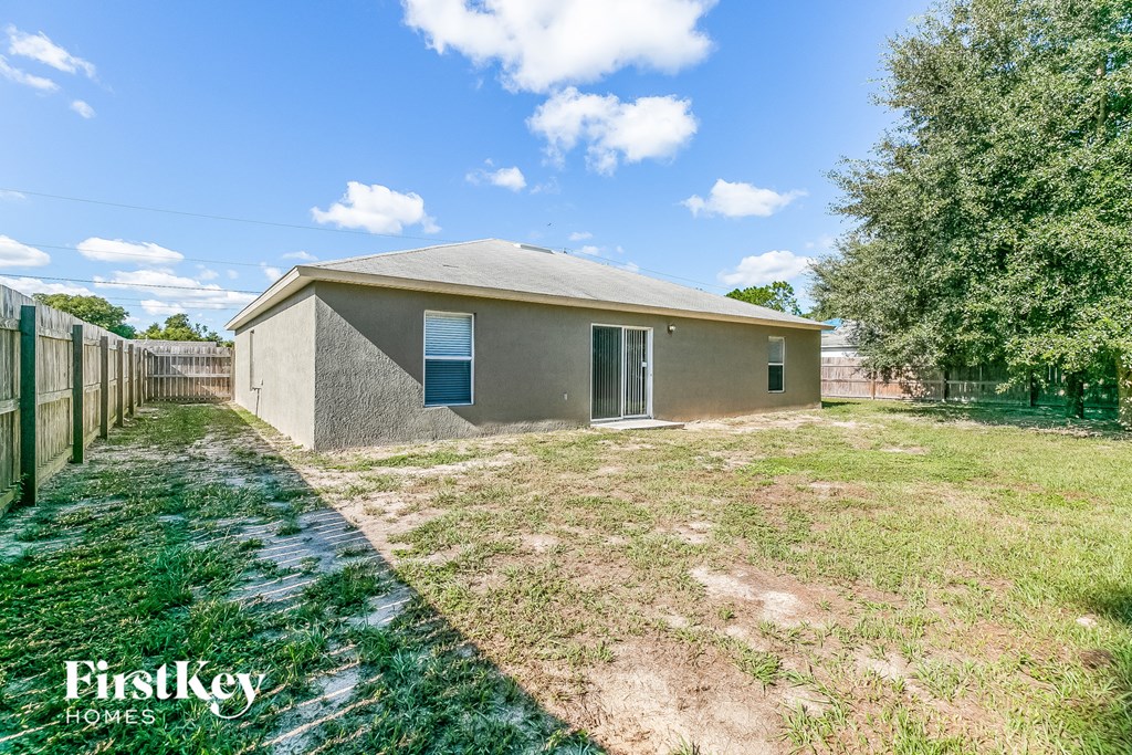 a small brick house with a grass yard and a fence